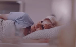 خانم مسنی که بر روی تخت دراز کشیده است و با بی‌خوابی دست و پنجه نرم می‌کند